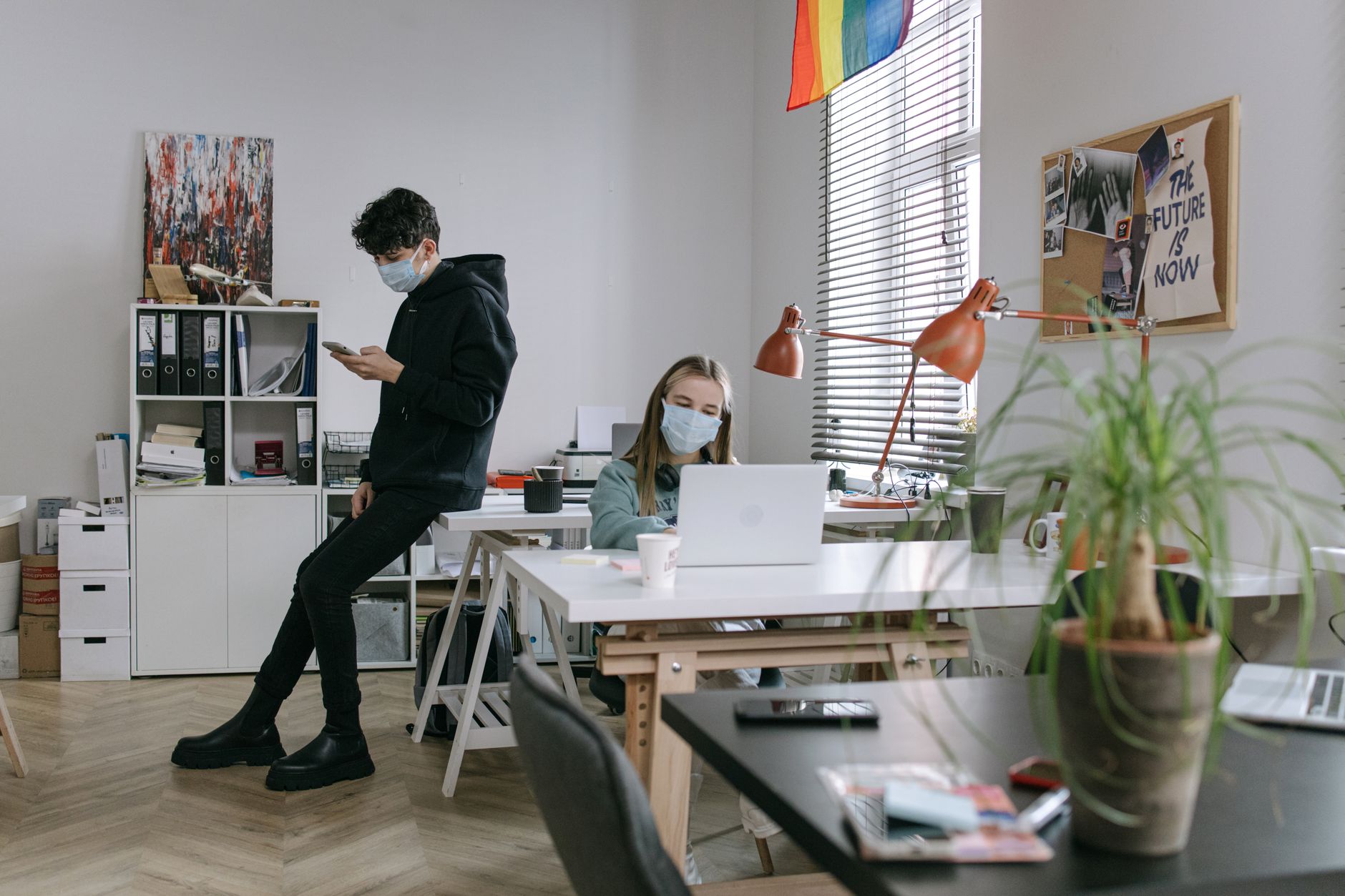 Two masked individuals working in a contemporary office setting, embracing the new normal.