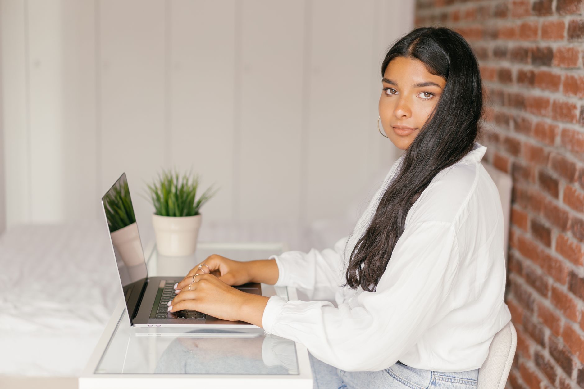 A young woman sits at a desk working on a laptop in her home office.