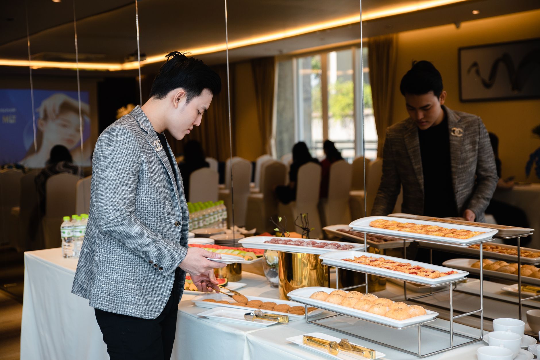 Man selecting pastries from a buffet at a corporate event indoors.