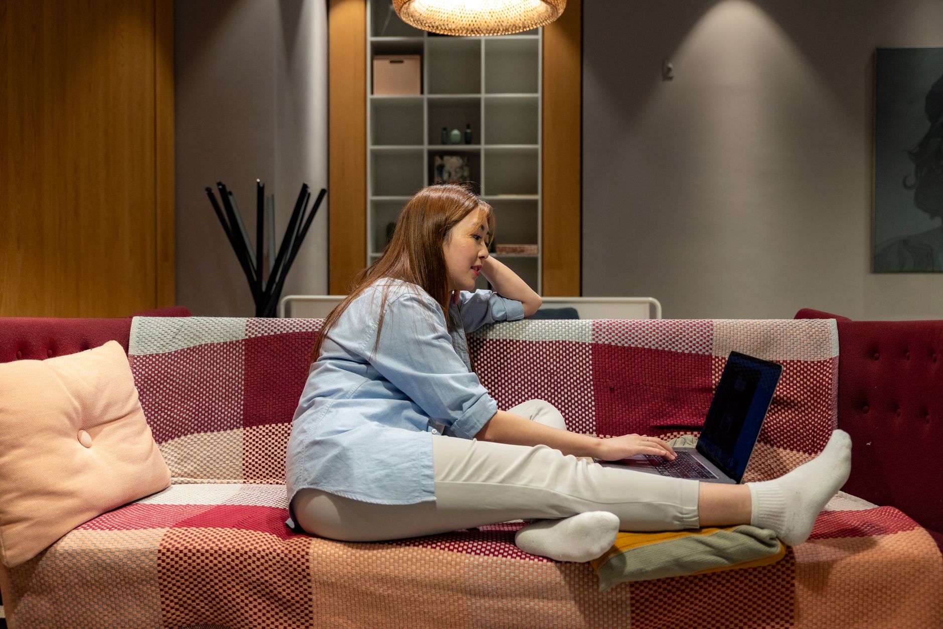 Woman working on a laptop in a cozy indoor environment, embodying the remote work lifestyle.