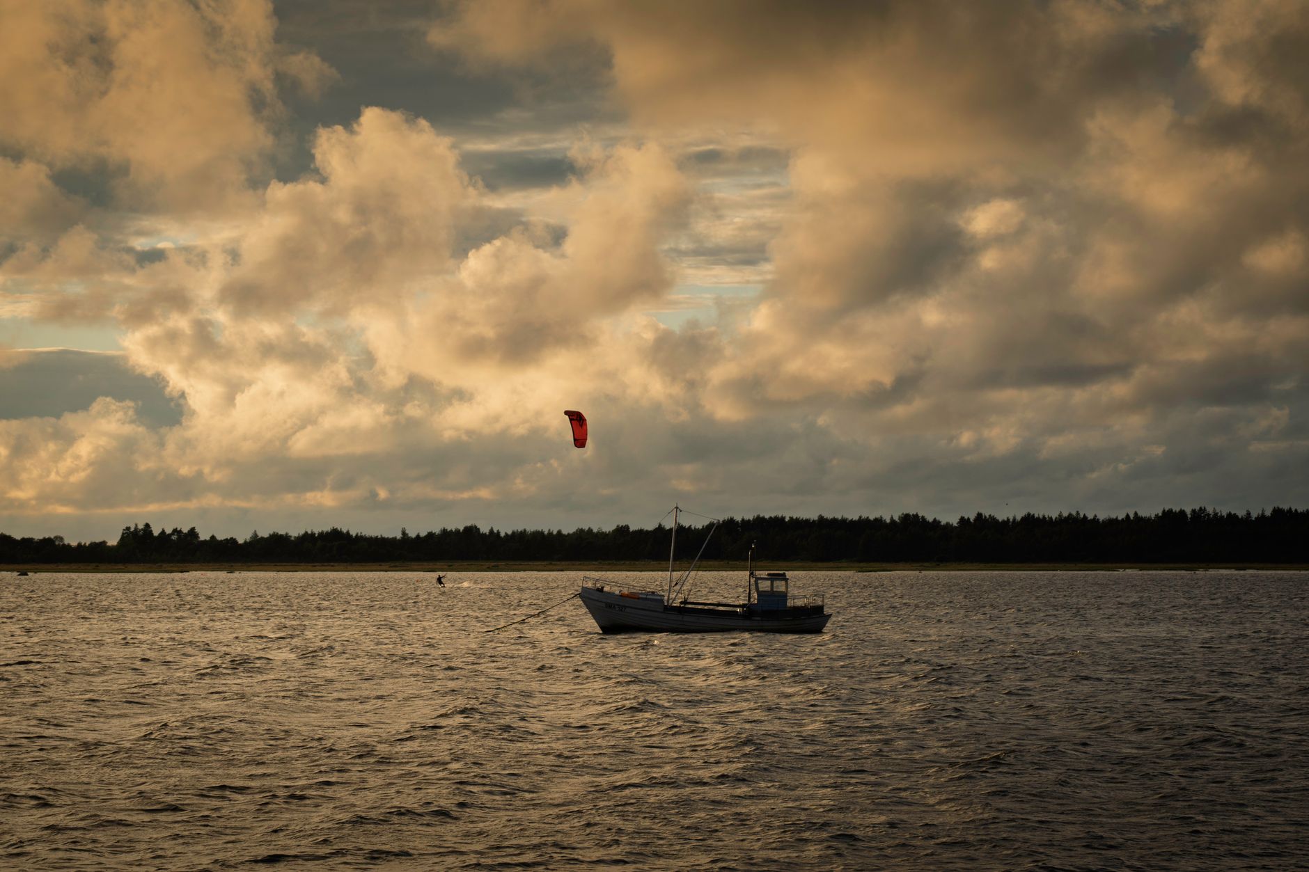 A tranquil scene of a lone boat and kite under dramatic evening clouds in Vilsandi, Estonia.