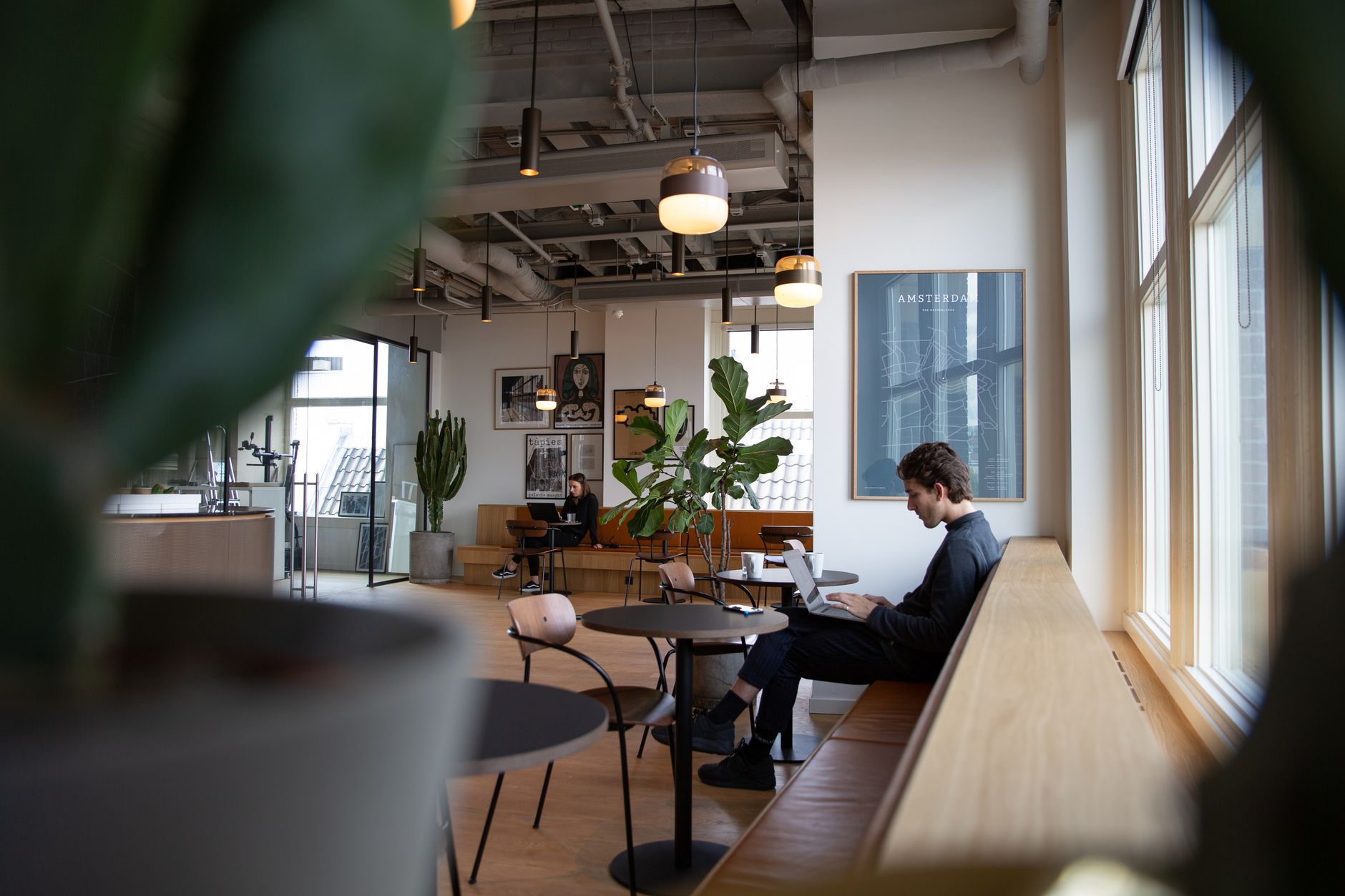 Modern coworking space in Amsterdam with a relaxed ambiance, featuring individuals working on laptops.