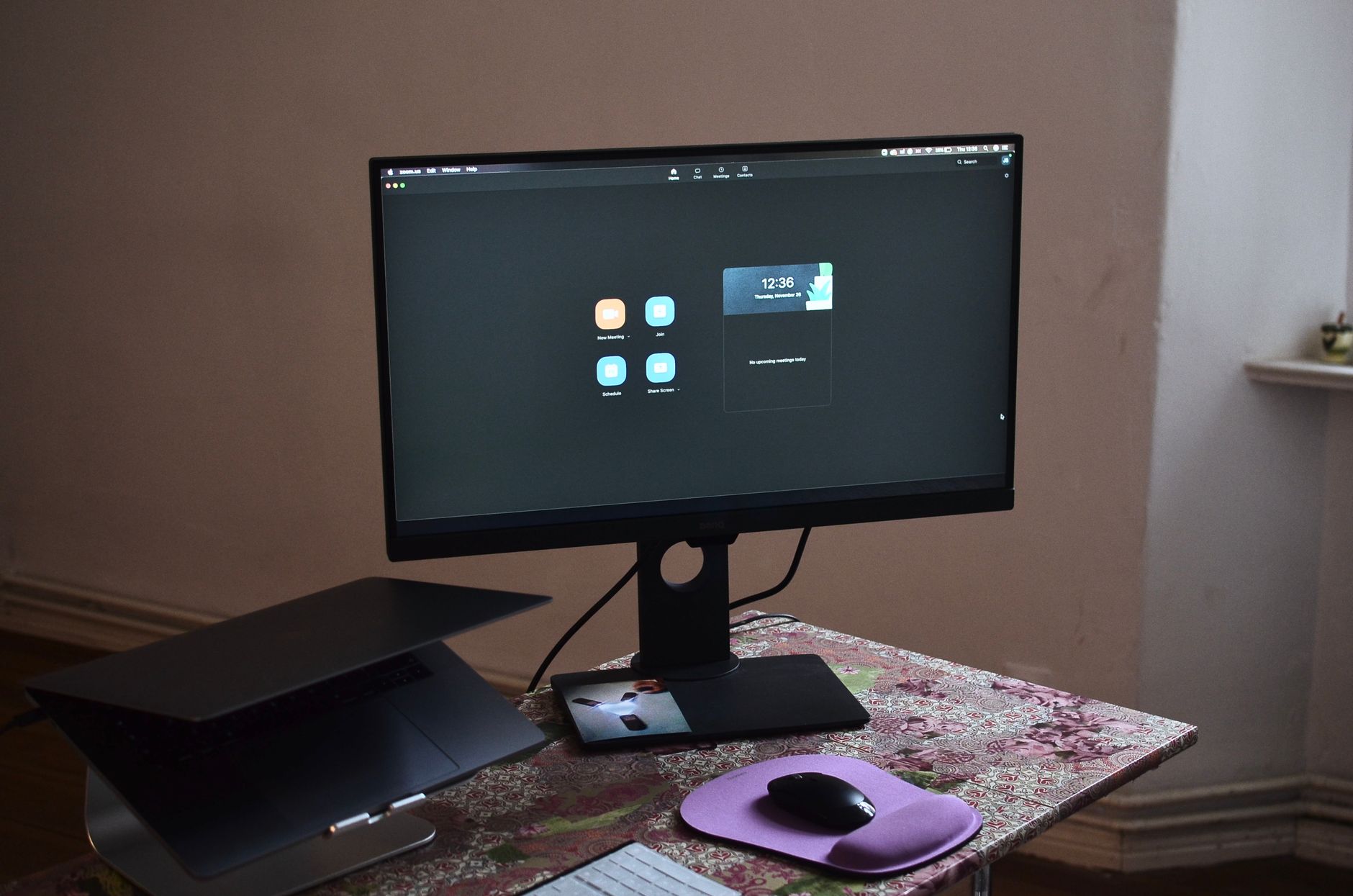 From above of netbook on stand and monitor with interface placed on desk with keyboard and mouse at convenient workspace