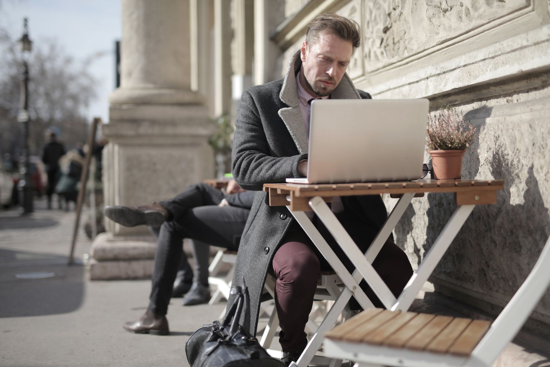 Freelancer working on laptop outdoors in urban area, embracing remote work lifestyle.