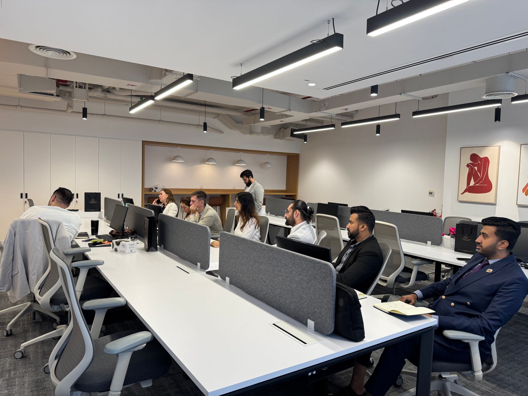 Diverse team working in a modern office setting with computers and collaborative spaces.