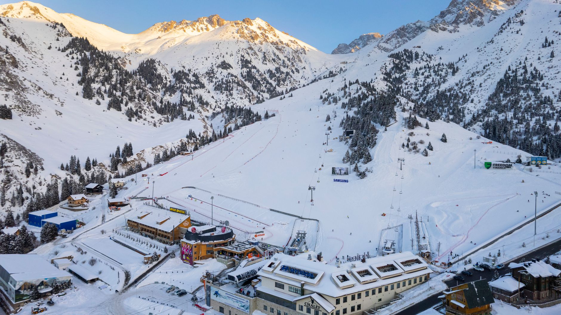 Aerial view of a ski resort in Almaty, Kazakhstan with snowy mountains and clear skies.